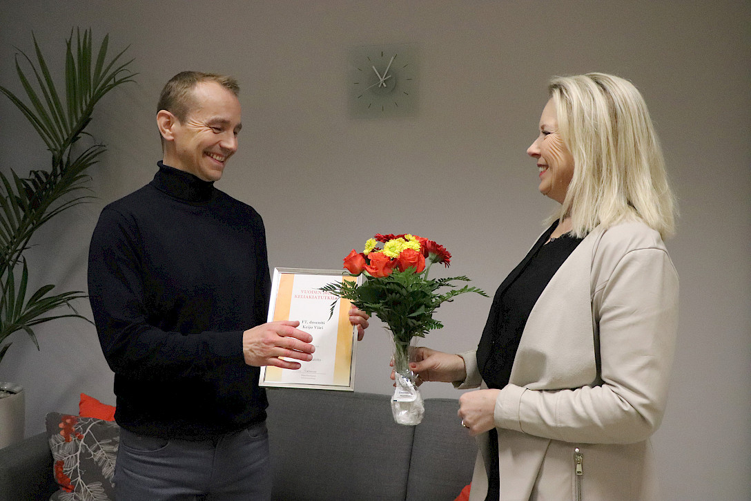 Toiminnanjohtaja Niina Puronurmi ojentaa vuoden keliakiatutkijalle Keijo Viirille kunniakirjan ja kukat.